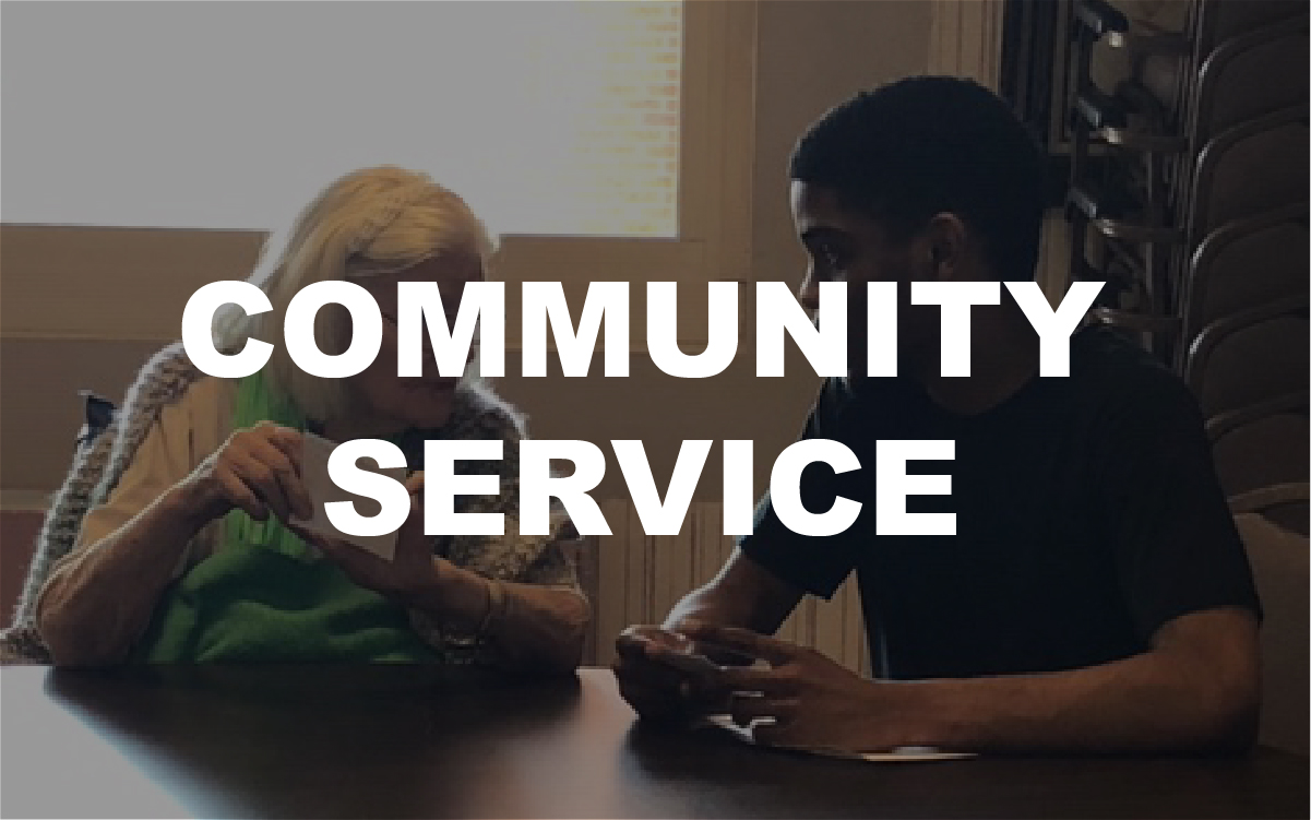 Student sitting with elderly woman during community service visit