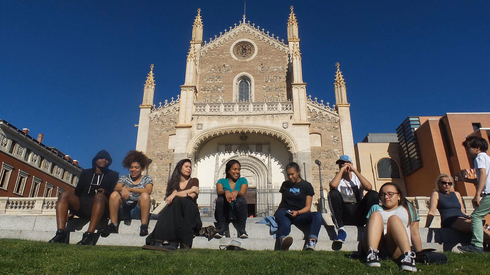 Students sitting on steps in front of a historic European cathedral