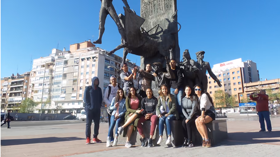 Students posing beside a large bronze sculpture in a city plaza