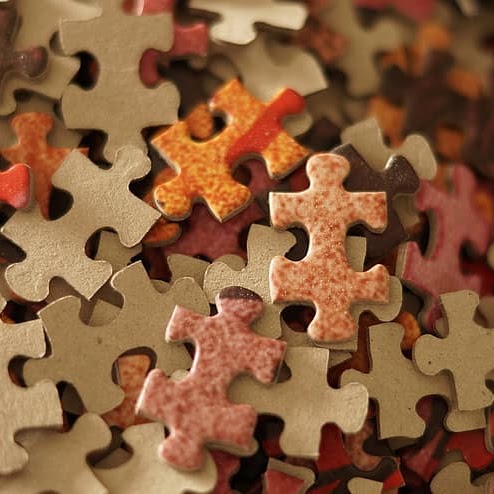 Scattered unassembled jigsaw puzzle pieces in warm earth tones