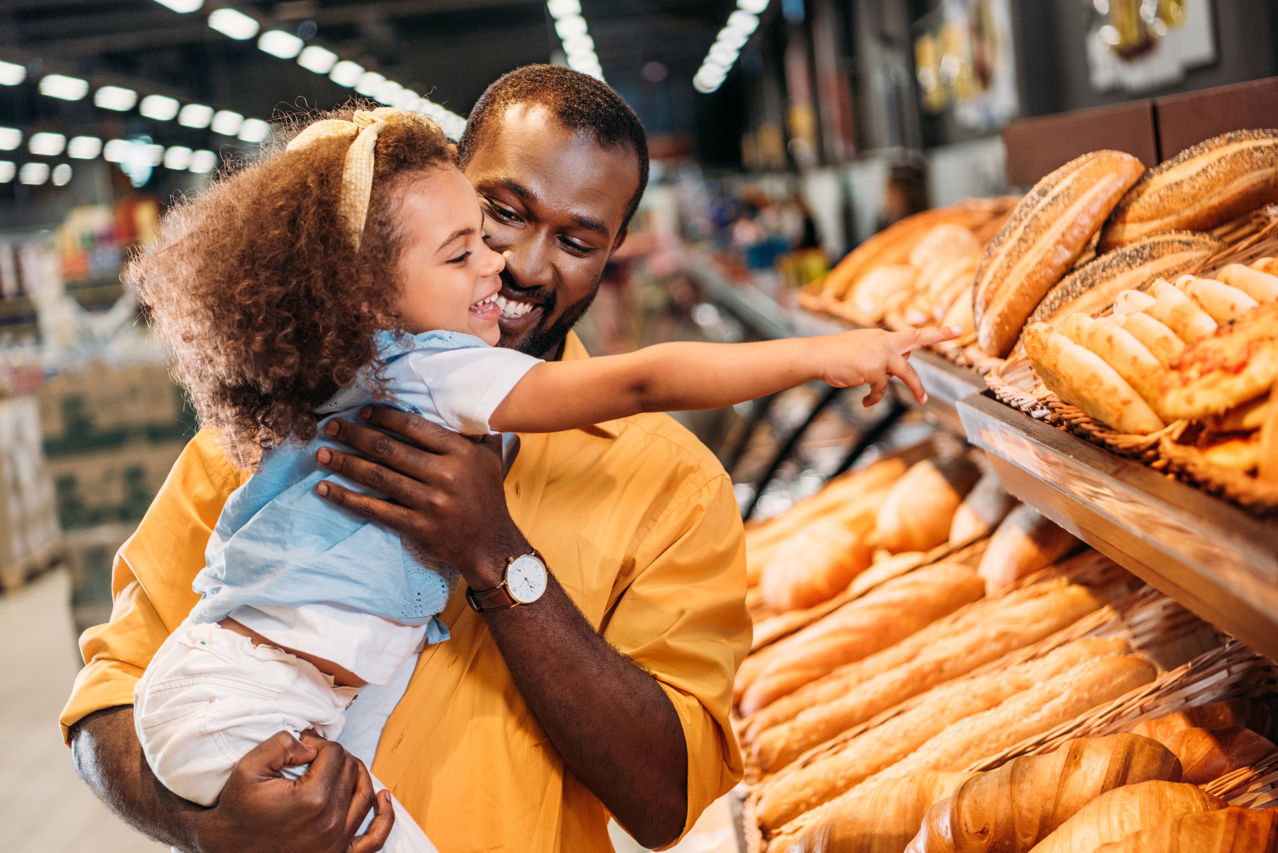 Father holding daughter pointing to bread stock image