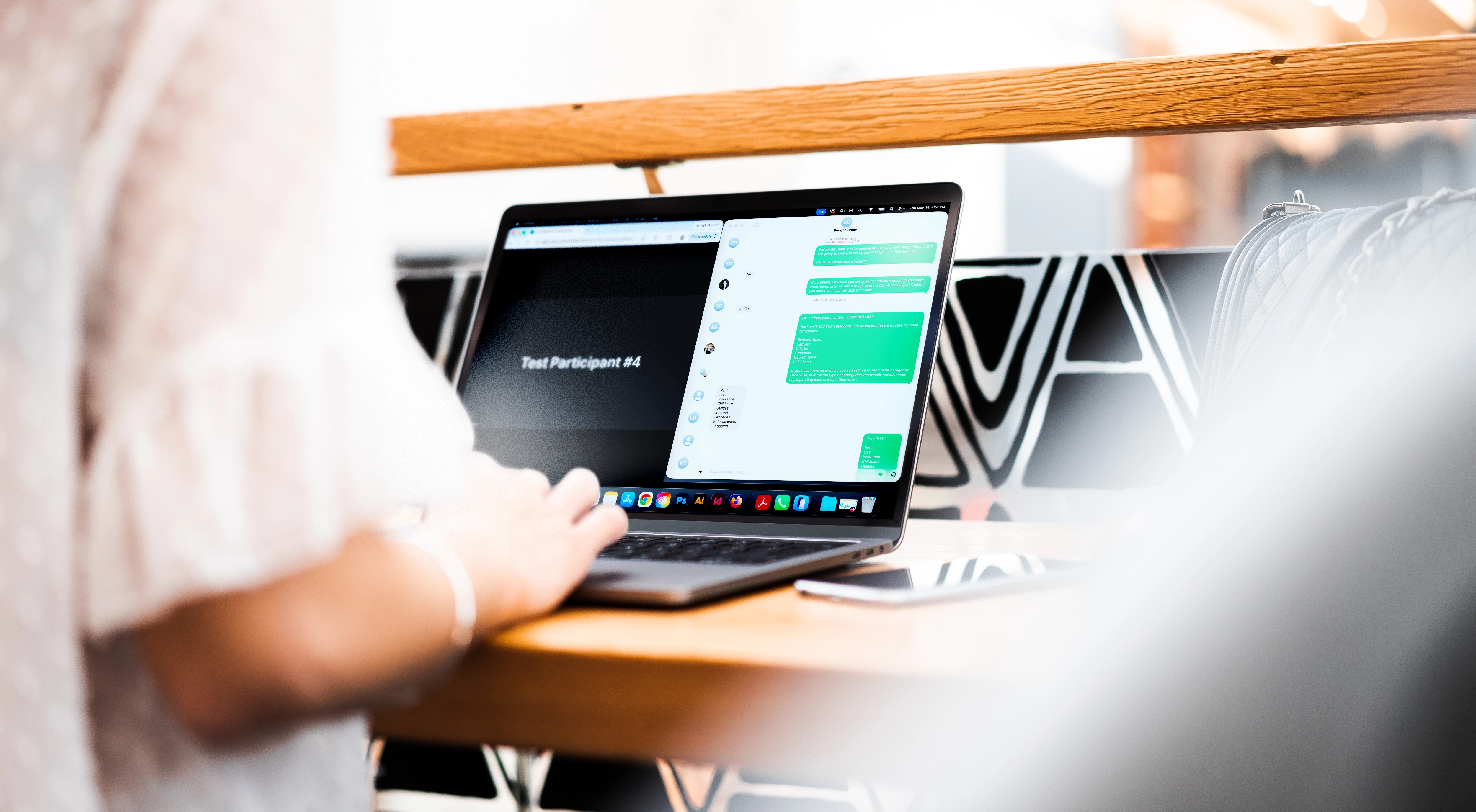 Person typing on a laptop with a chat app and video call screen visible on a wooden table.