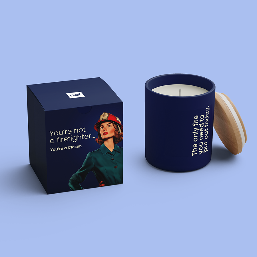 Navy blue candle with wooden lid and matching box showing a woman firefighter and motivational text.