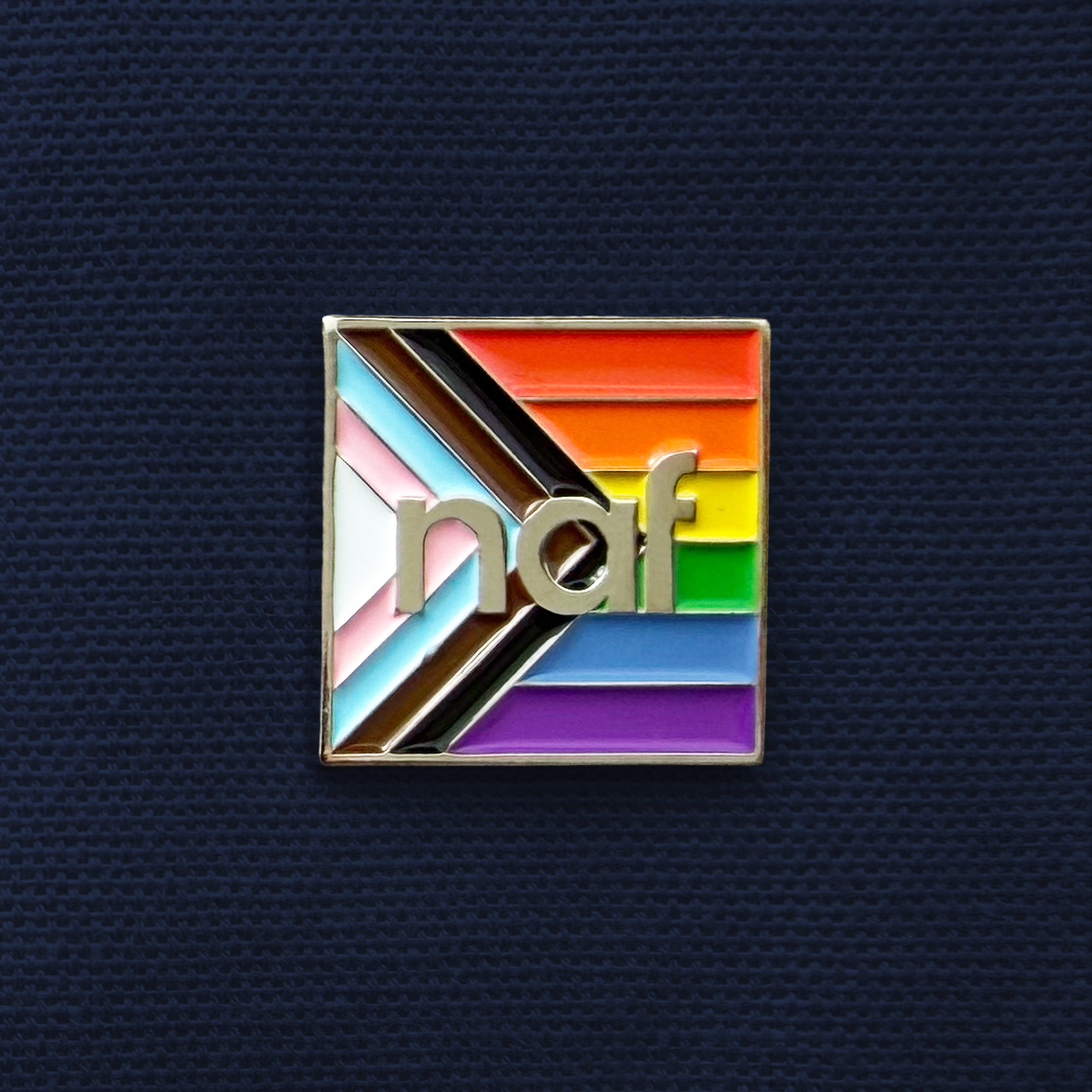 Square pride flag pin with rainbow and trans colors and silver letters "naf" in the center.