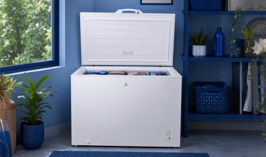 White Haier chest freezer with open lid in a bright kitchen corner with light wood flooring.