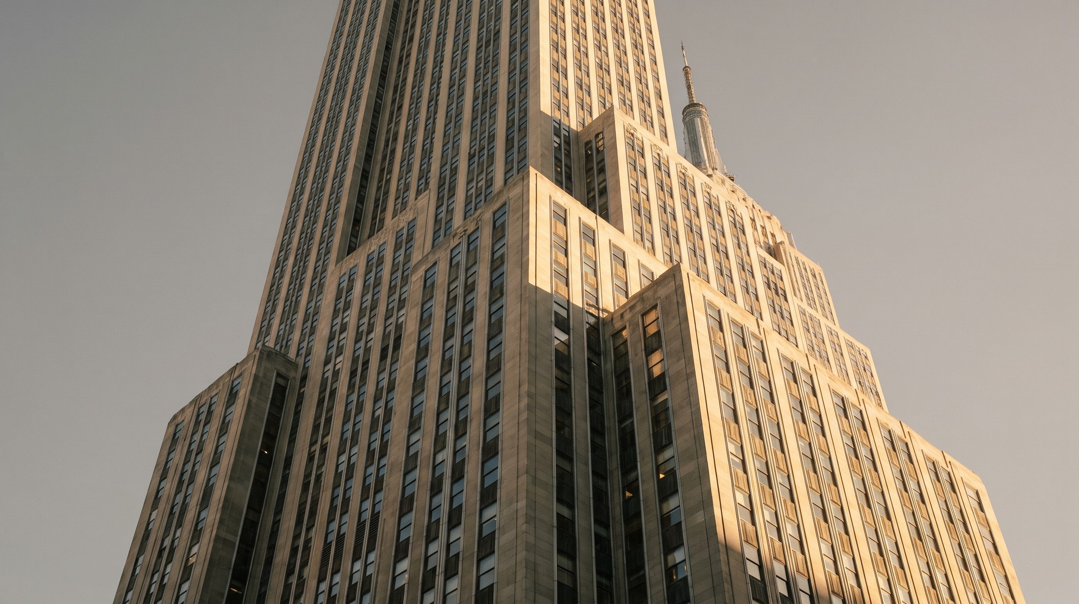 The Empire State Building in New York City, its Art Deco setbacks clad in Indiana limestone, photographed from street level in late afternoon light.