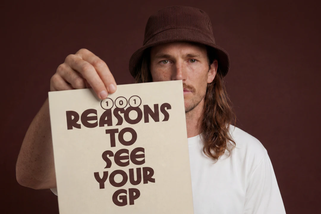 Man with long hair and mustache wearing a brown bucket hat and white shirt, eyes closed.