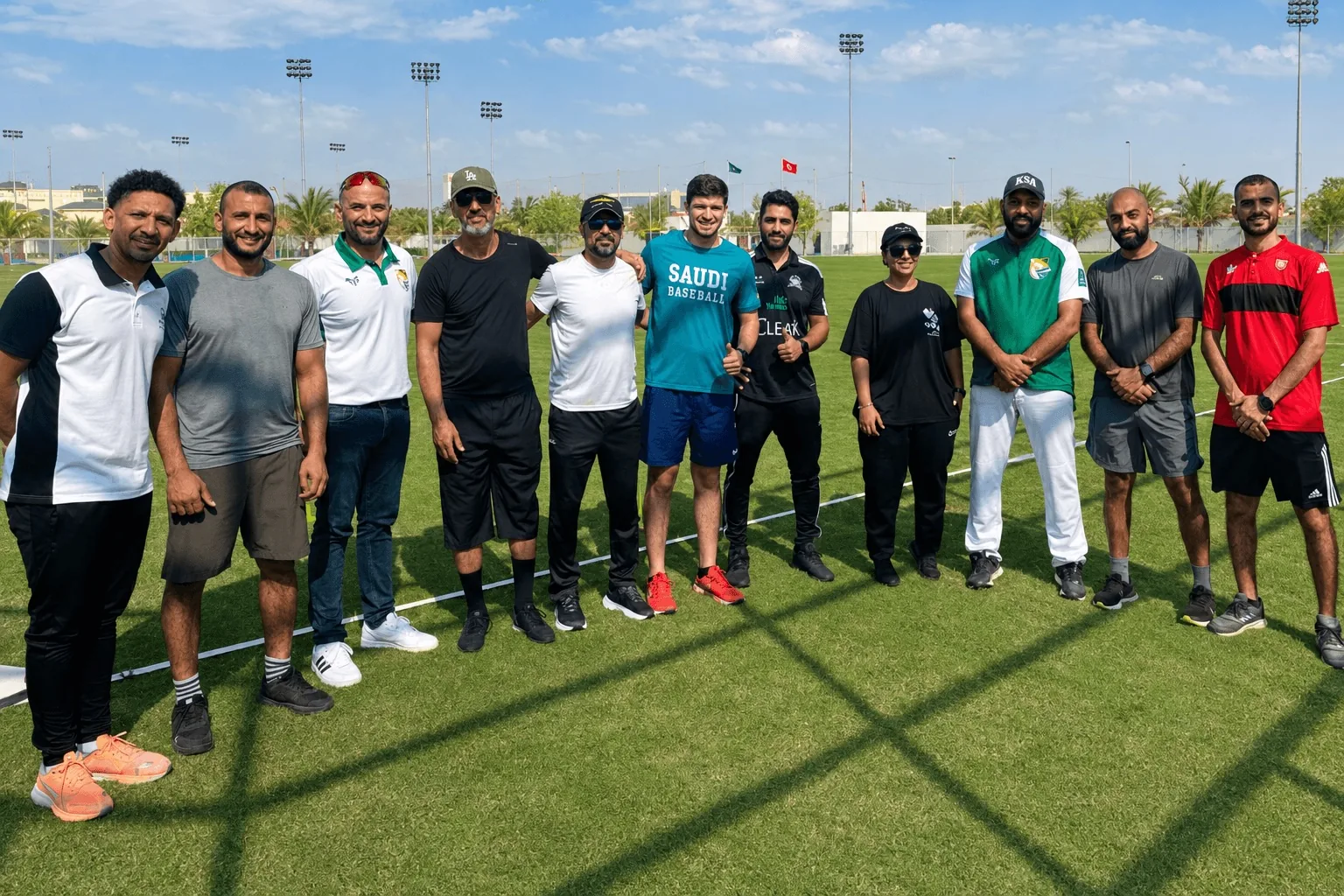 School sport leaders and federation partners stand together on a playing field in Jeddah.