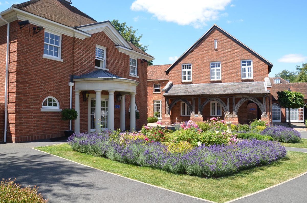 Red-brick buildings around a garden of lavender and roses on the TASIS England campus