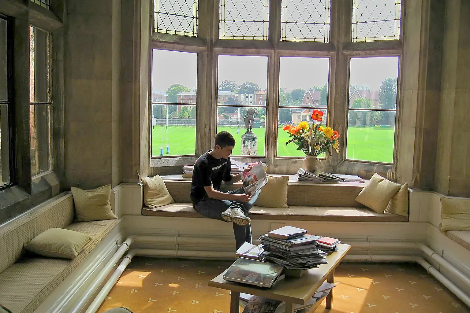 A boy reading on a window seat in the library, looking out over the Close.
