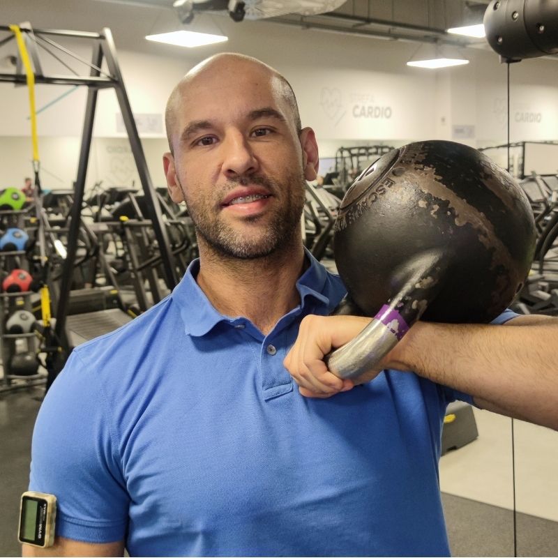Doświadczony trener medyczny Wrocław z kettlebell na ramieniu – profesjonalny trening siłowy i medyczny