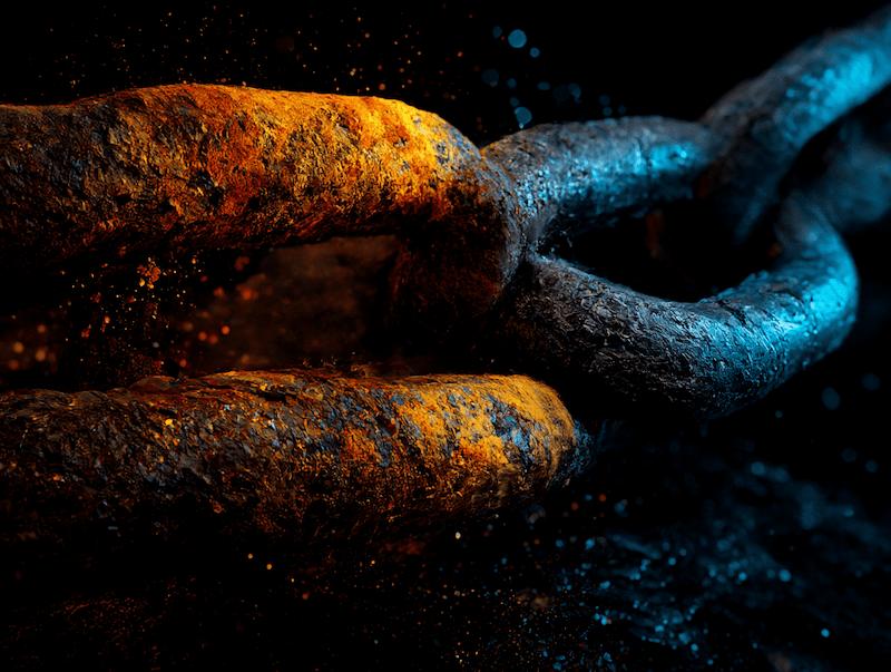 Close-up of a rusty metal chain link with orange and blue lighting effects.