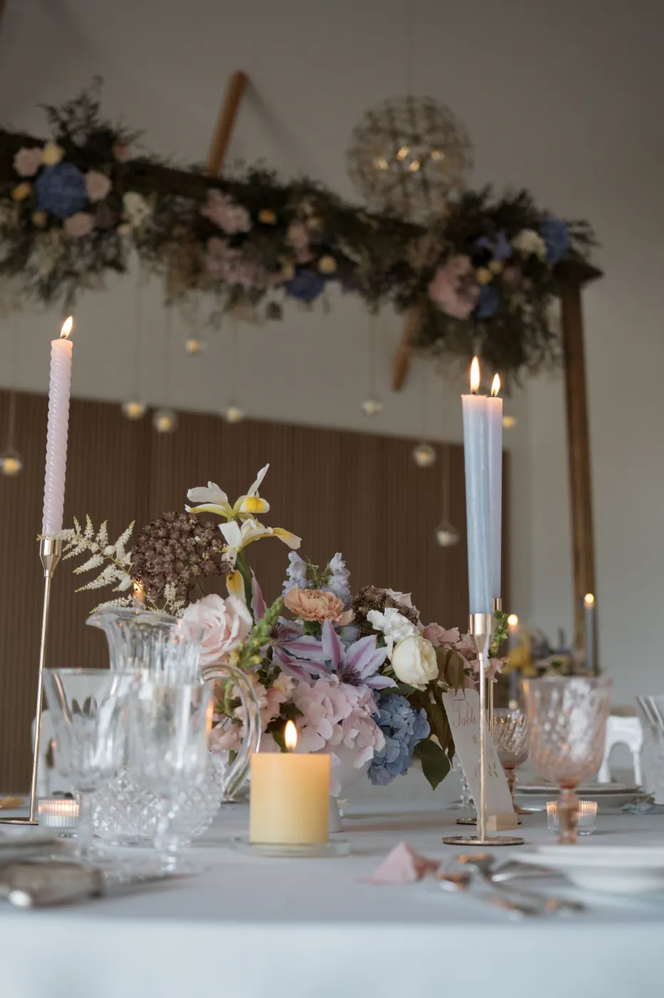 Détail floral de table avec bougies pastel et bouquet pour événement privé au Clos de Montgay
