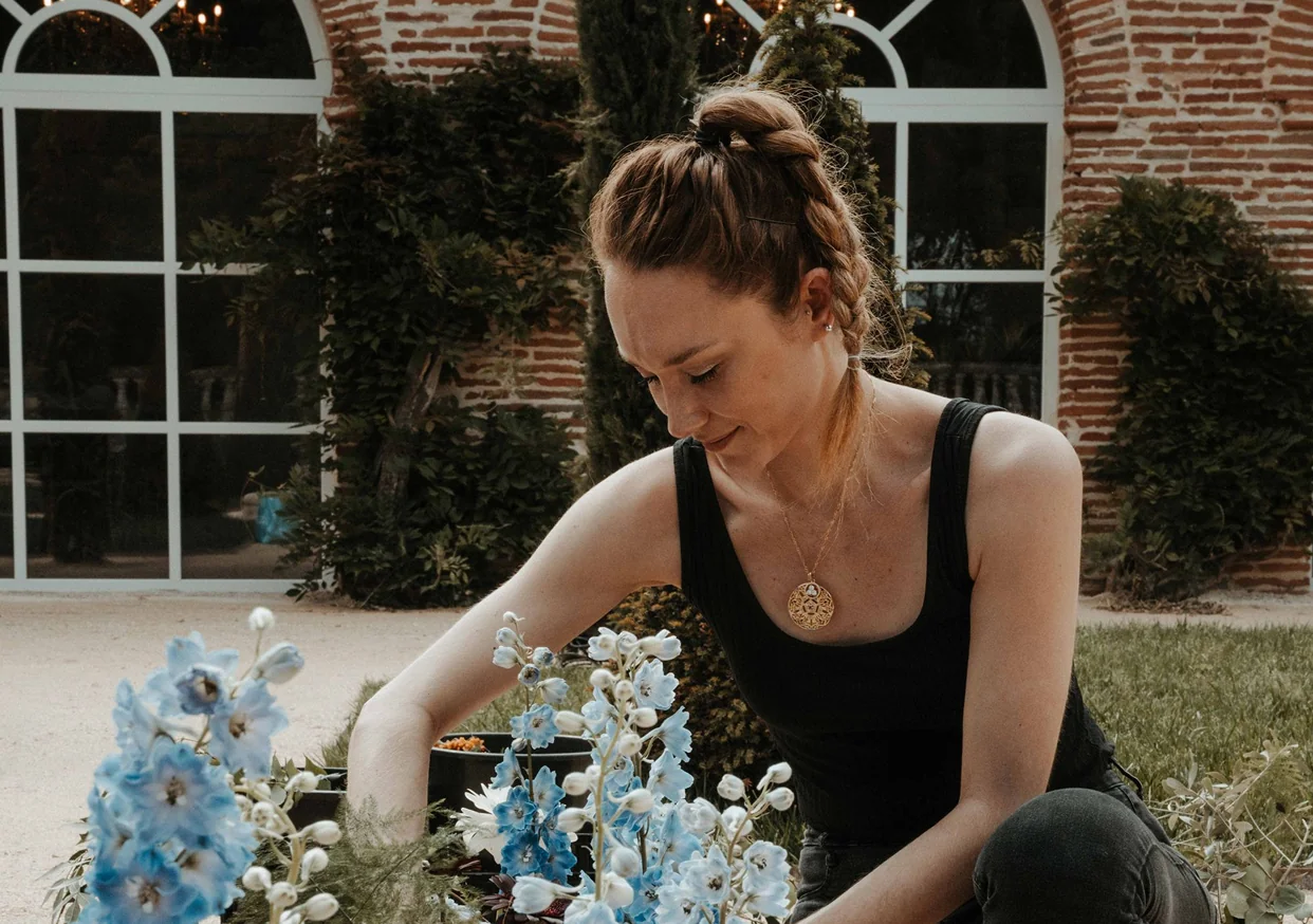 Julia, fleuriste de Flower in Love, composant un arrangement de delphiniums bleus