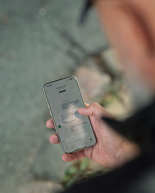 Persoon die een smartphone vasthoudt en een chatbericht op het scherm bekijkt.