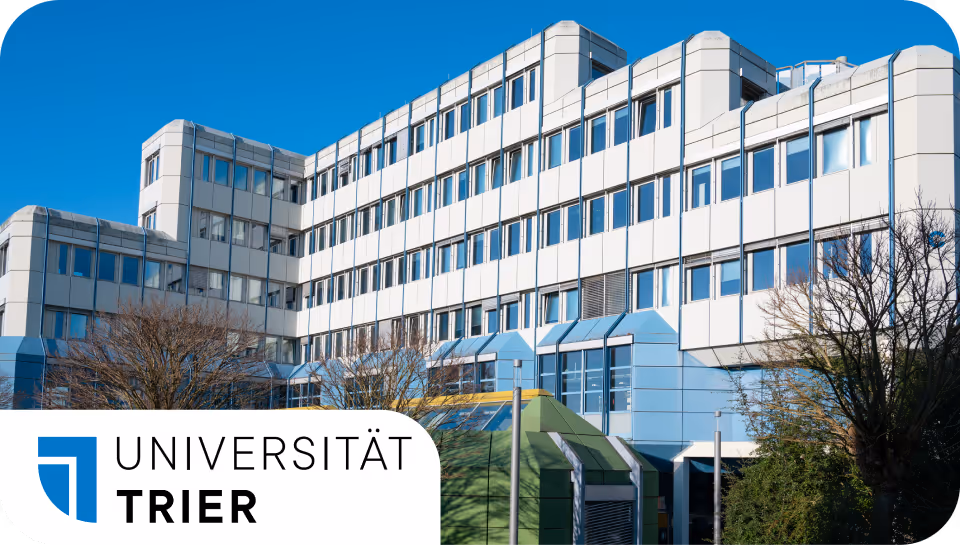 Modernes Uni-Gebäude der Universität Trier vor blauem Himmel mit Bäumen im Vordergrund.