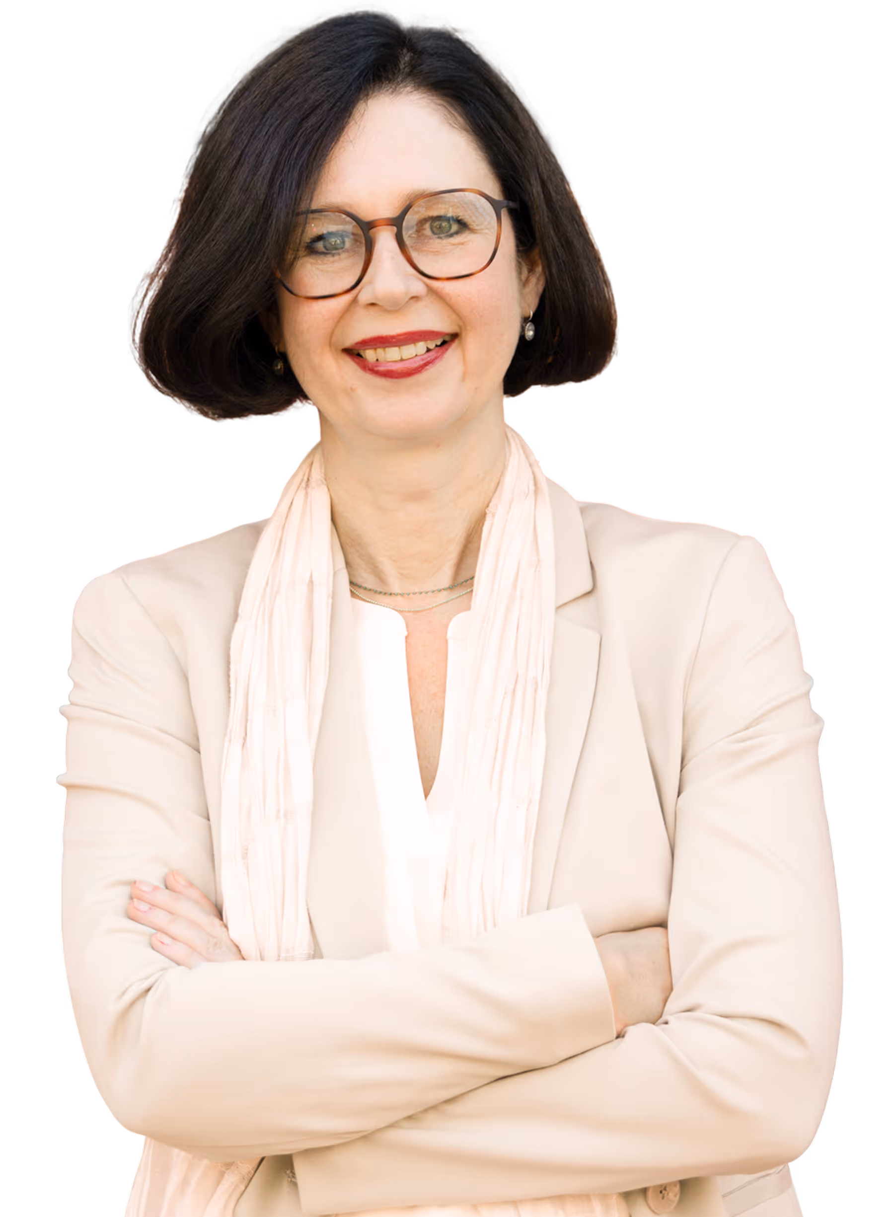 Frau mittleren Alters mit Brille, dunkelbraunem Bob, beige Blazer und Schal, lächelnd mit verschränkten Armen.