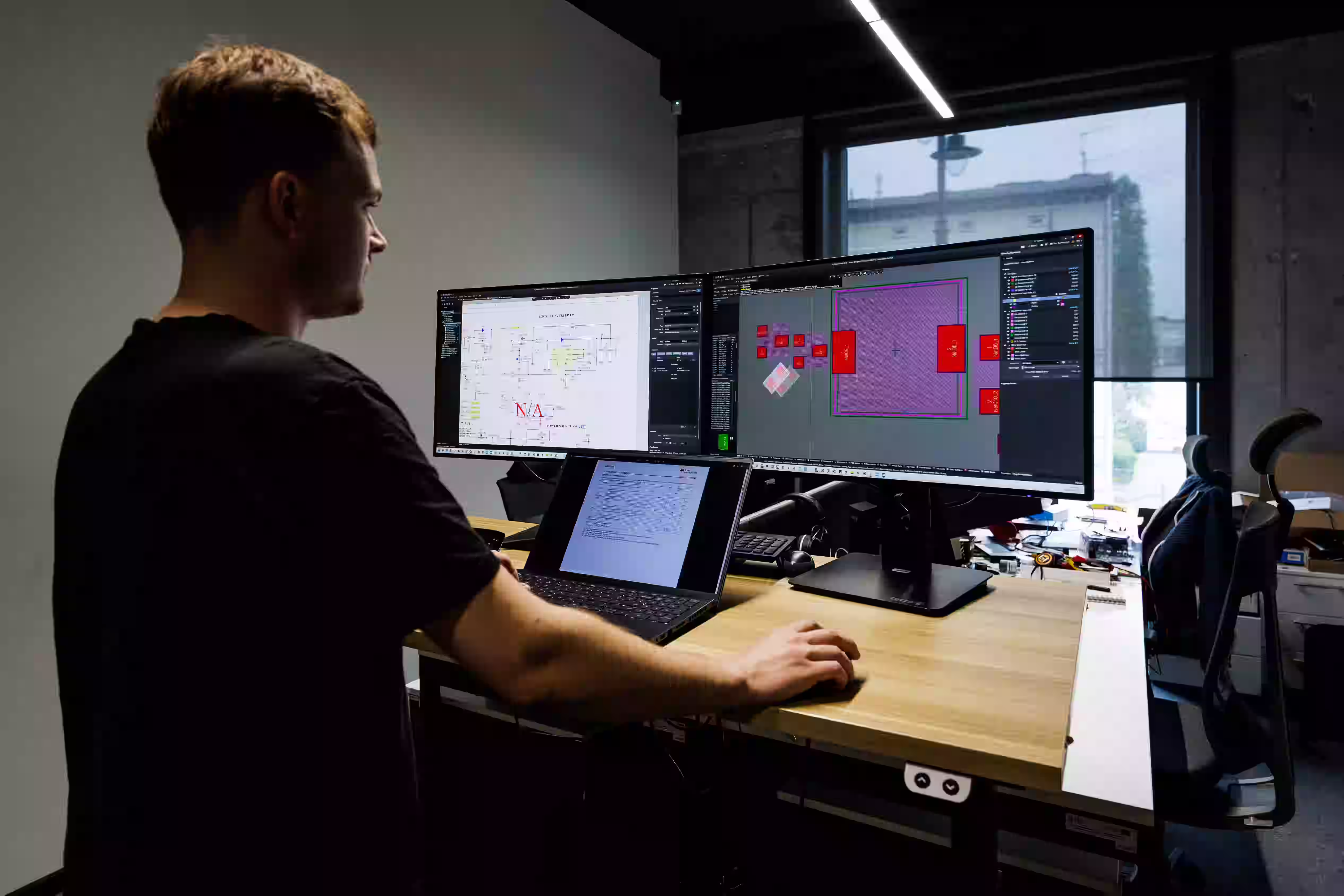 Engineer reviewing circuit schematic and PCB layout on dual monitors