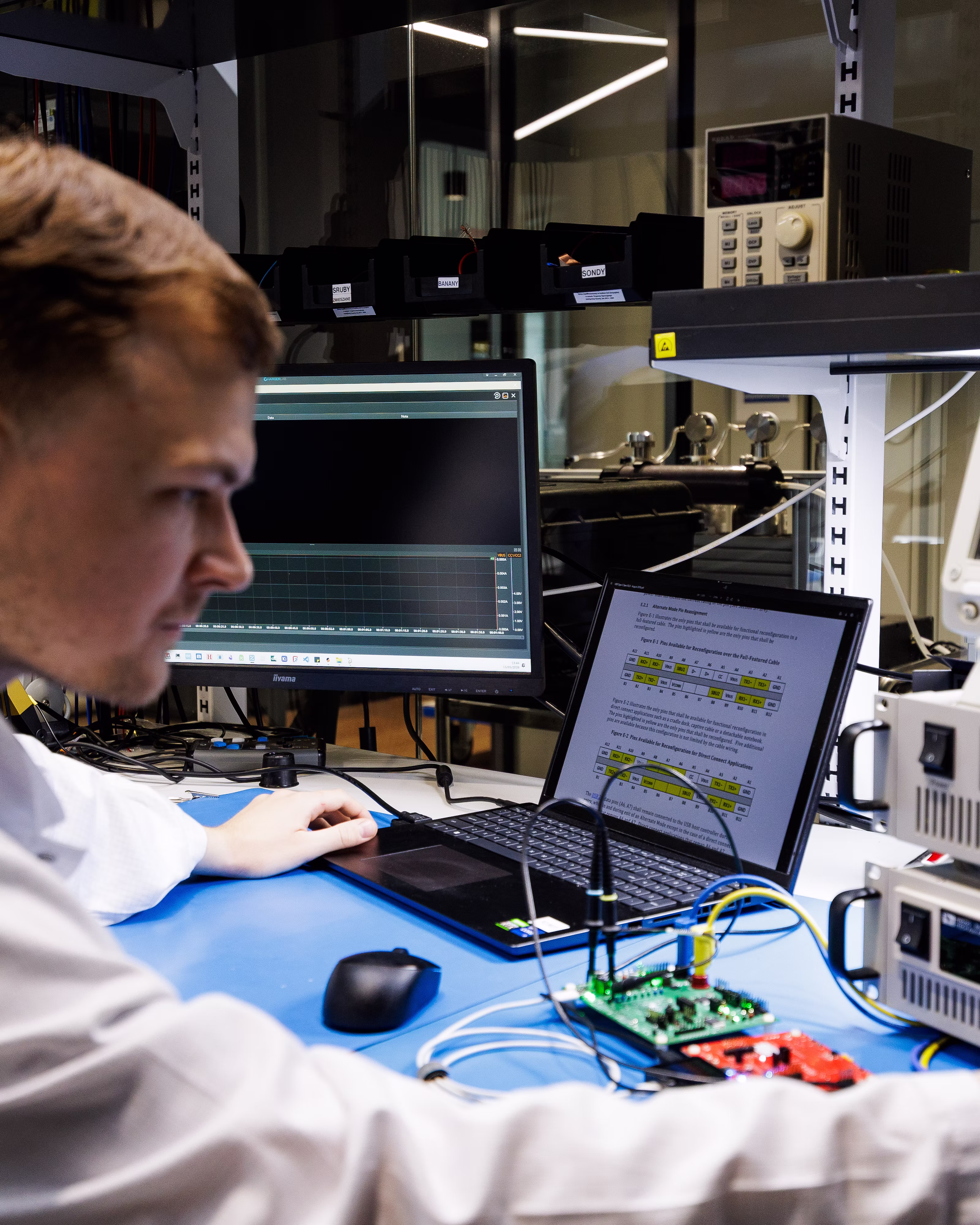 Engineer testing an electronic circuit board with laboratory measurement equipment.