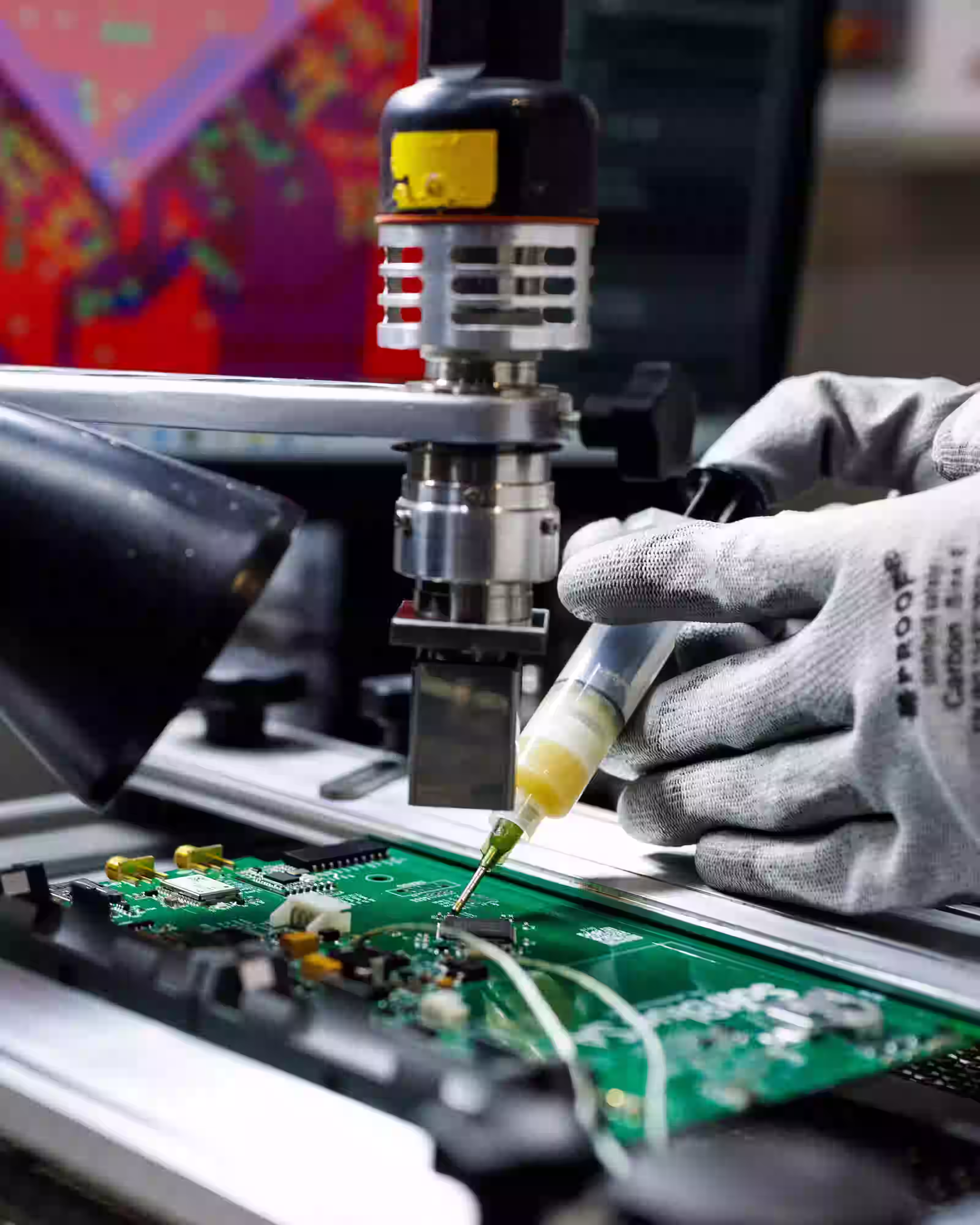 Technician applying material to a circuit board during precision electronics assembly.