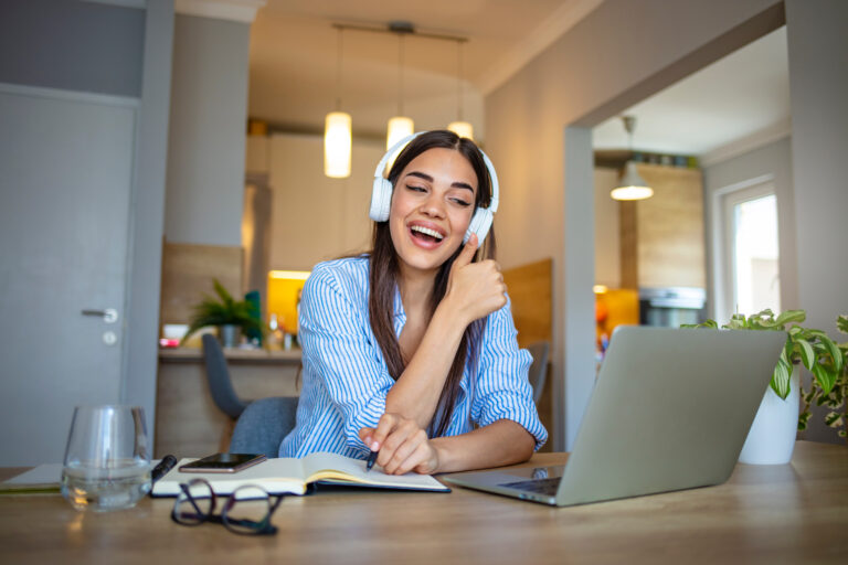Woman wearing headphones on a video call at a laptop while working from home
