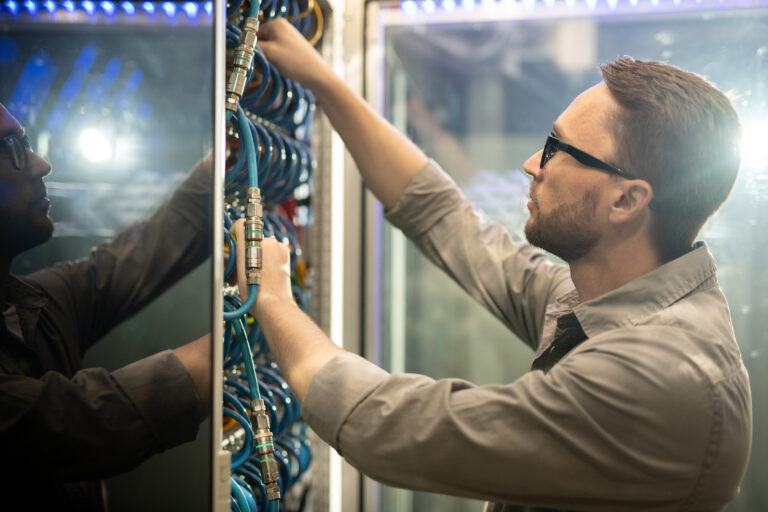 IT technician connecting network cables in a server rack