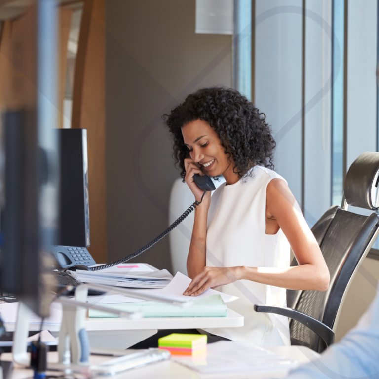 Businesswoman using a desk phone in a modern office, illustrating cloud telephony and business connectivity solutions in action.