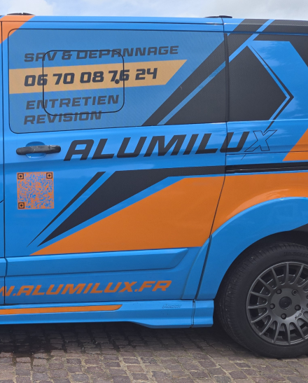Côté d'un camion bleu avec texte publicitaire d'Alumilux Agencement pour particuliers et pros.