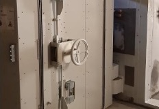 Porte métallique avec une roue de verrouillage ronde et un boîtier électrique fixé dessus.