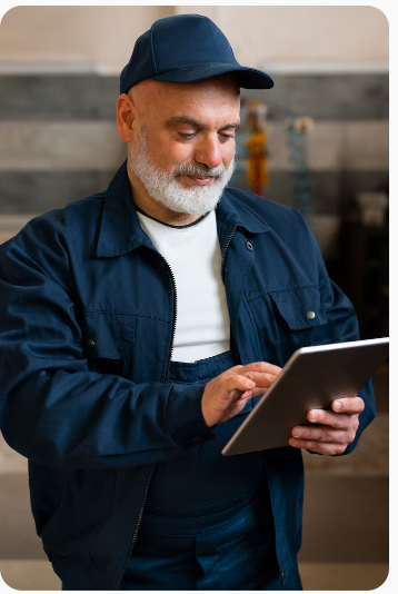 Homme âgé en veste bleue et casquette utilisant une tablette numérique avec un sourire.