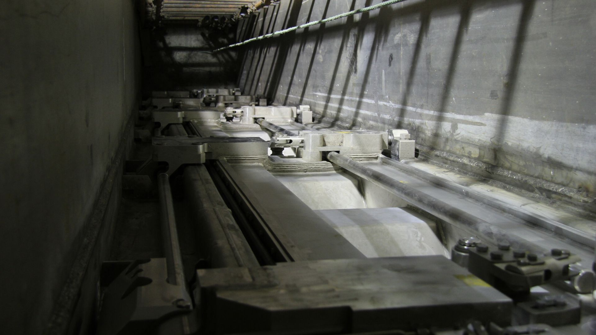 Vue rapprochée d'un mécanisme industriel avec des rails métalliques et des pièces mécaniques.