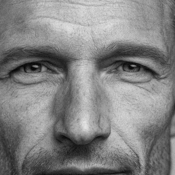 Primer plano en blanco y negro del rostro de un hombre con expresión seria y arrugas visibles.