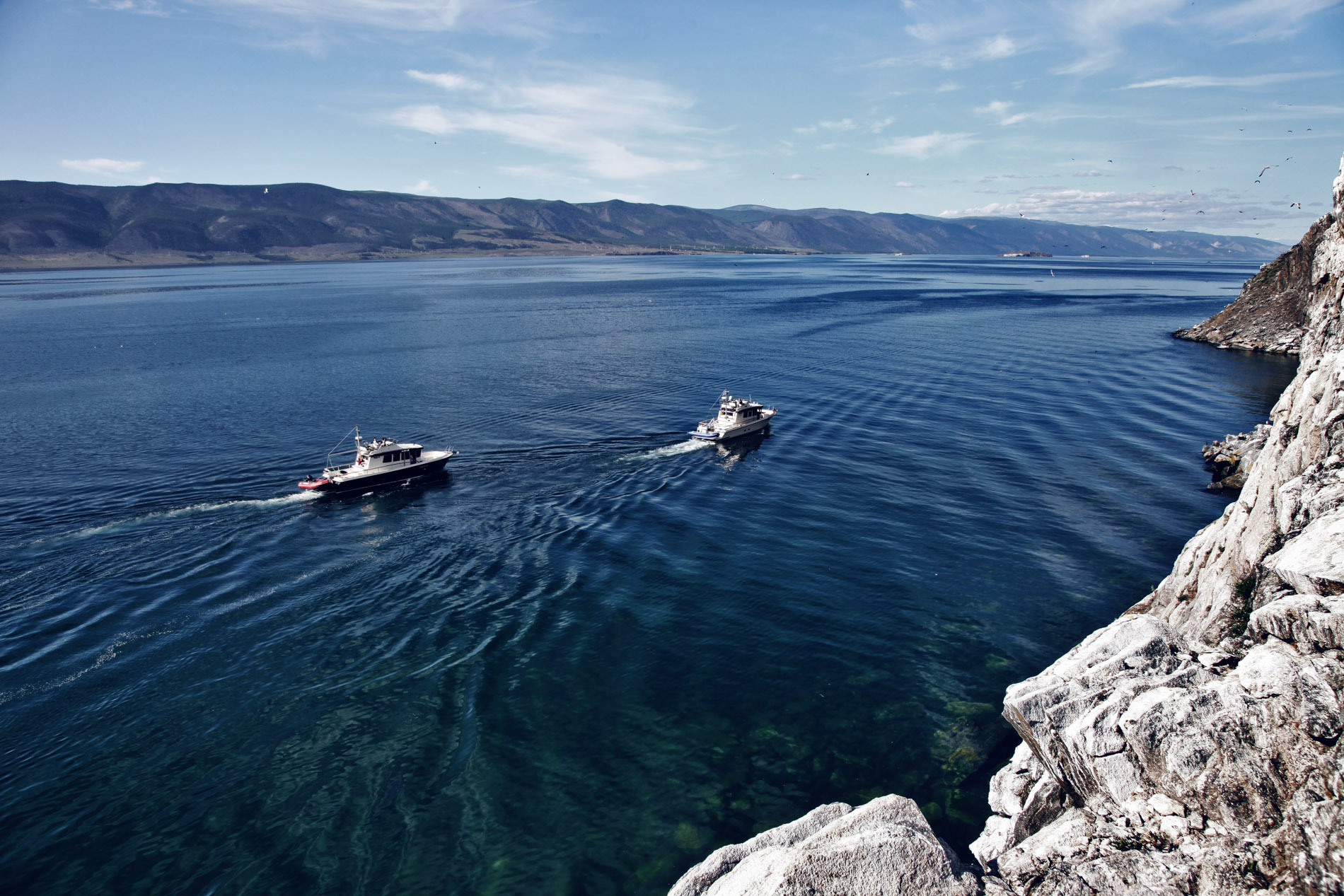Zwei Targas fahren durch einen Fjord.
