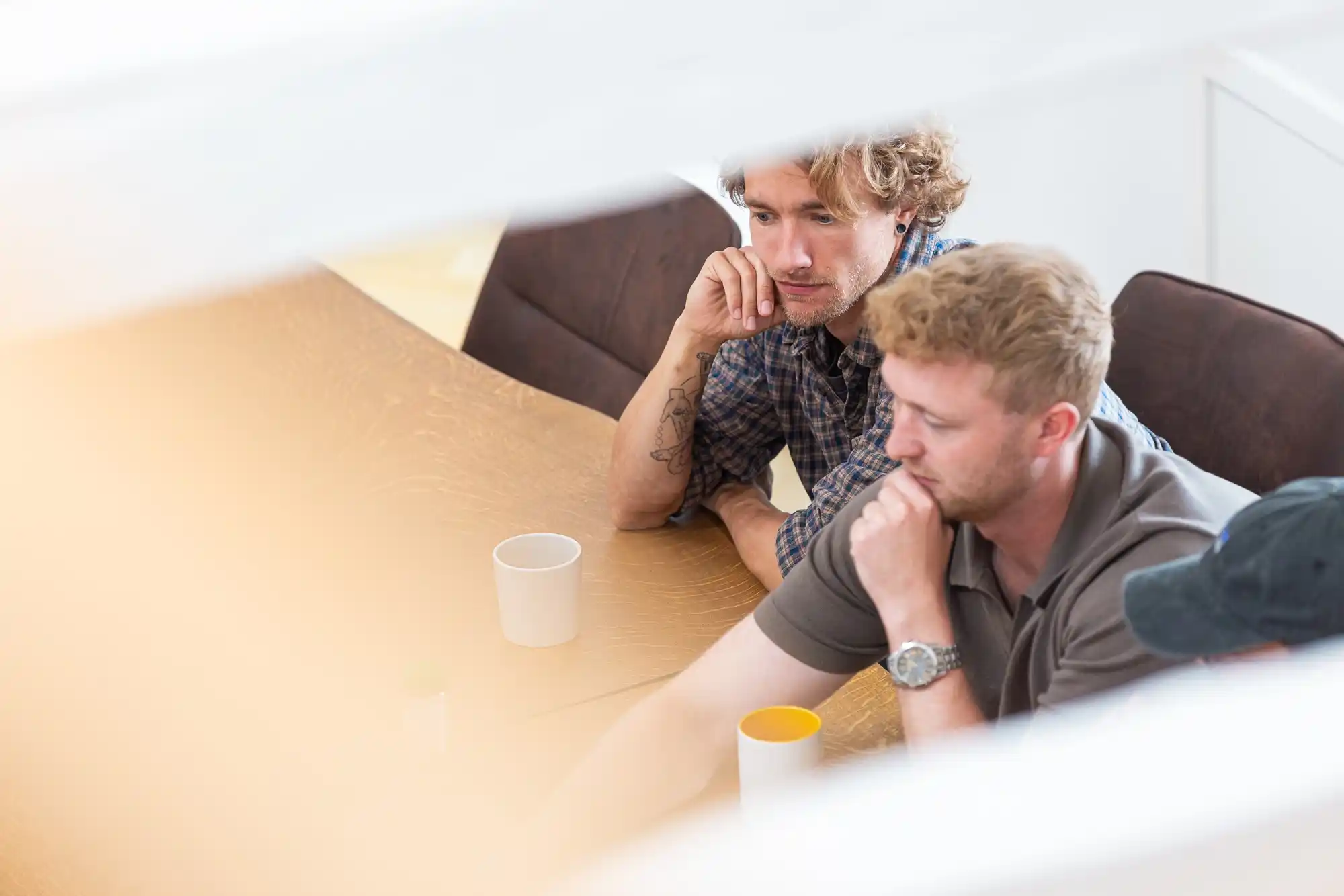 To mænd sidder ved et bord og ser koncentrerede ud under et møde eller arbejde.