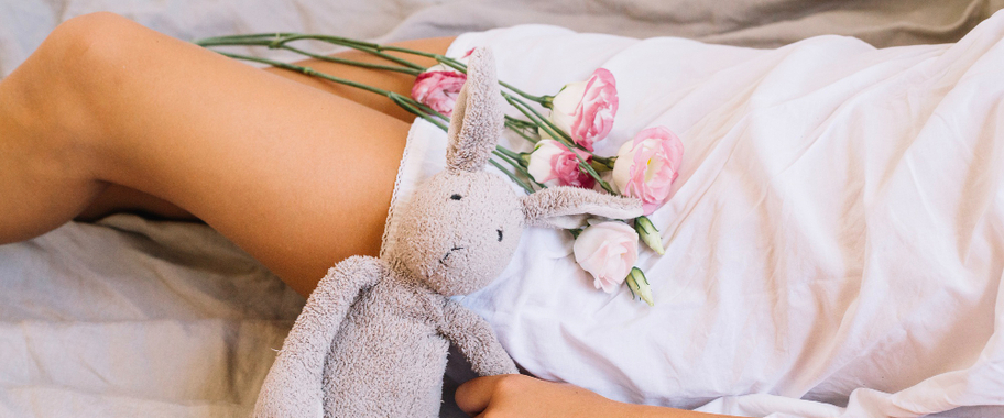 A woman lying on the bed wearing a white robe with flowers on her stomach