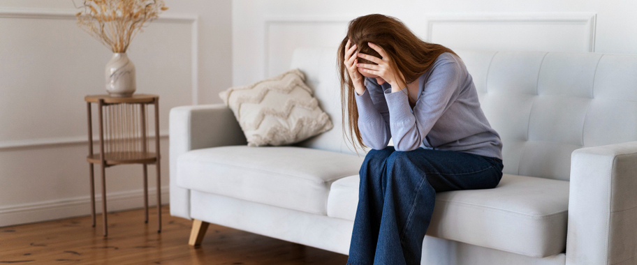 a person sitting on a sofa with their head in their hands