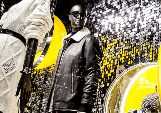 Mannequins standing in front of a silver sequin wall.