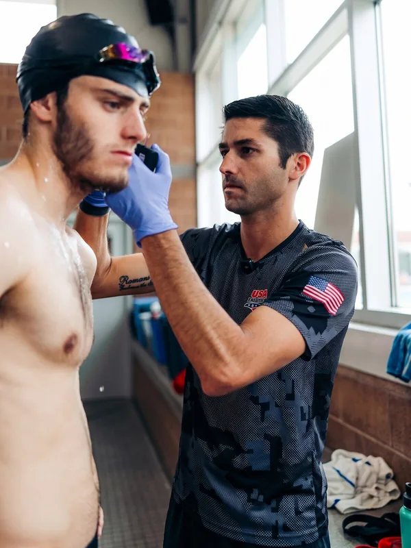 USA Triathlon coach taking an earlobe lactate sample from an athlete during field testing
