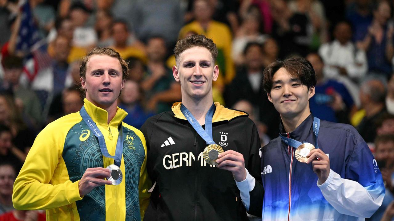 Gold medalist Lukas Martens (center) stands on the podium with silver medalist Elijah Winnington (left) and bronze medalist Woomin Kim (right)