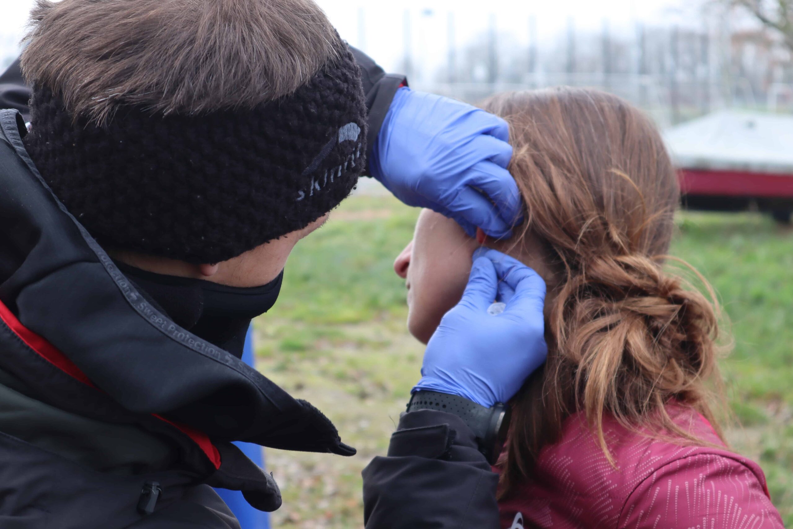 Athlete runner and coach performing a field test which includes measering blood lactate at earlobe