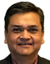 Smiling middle-aged man with short black hair wearing a dark shirt indoors.