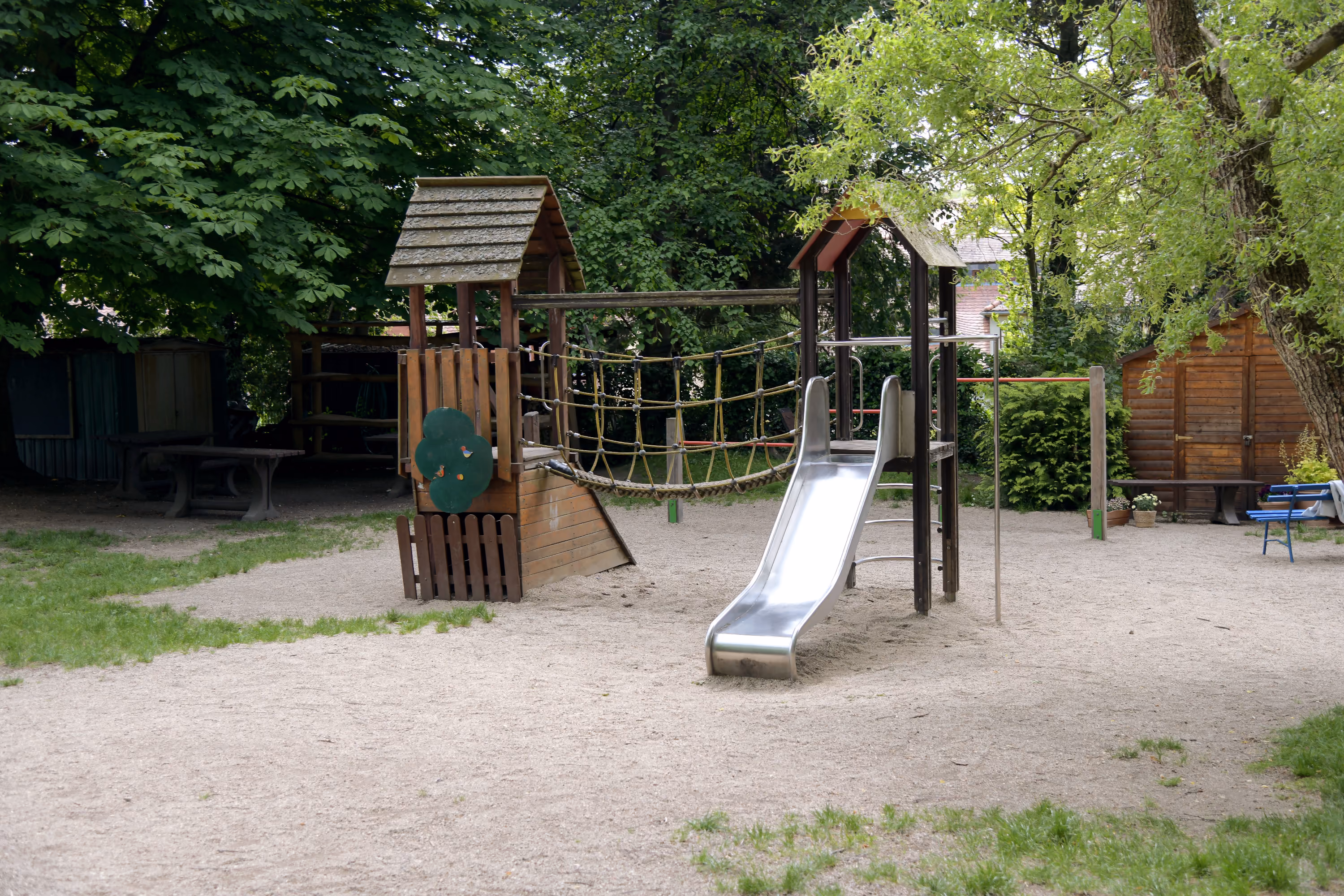 Klettergerüst mit Rutsche und Hängebrücke im Garten.
