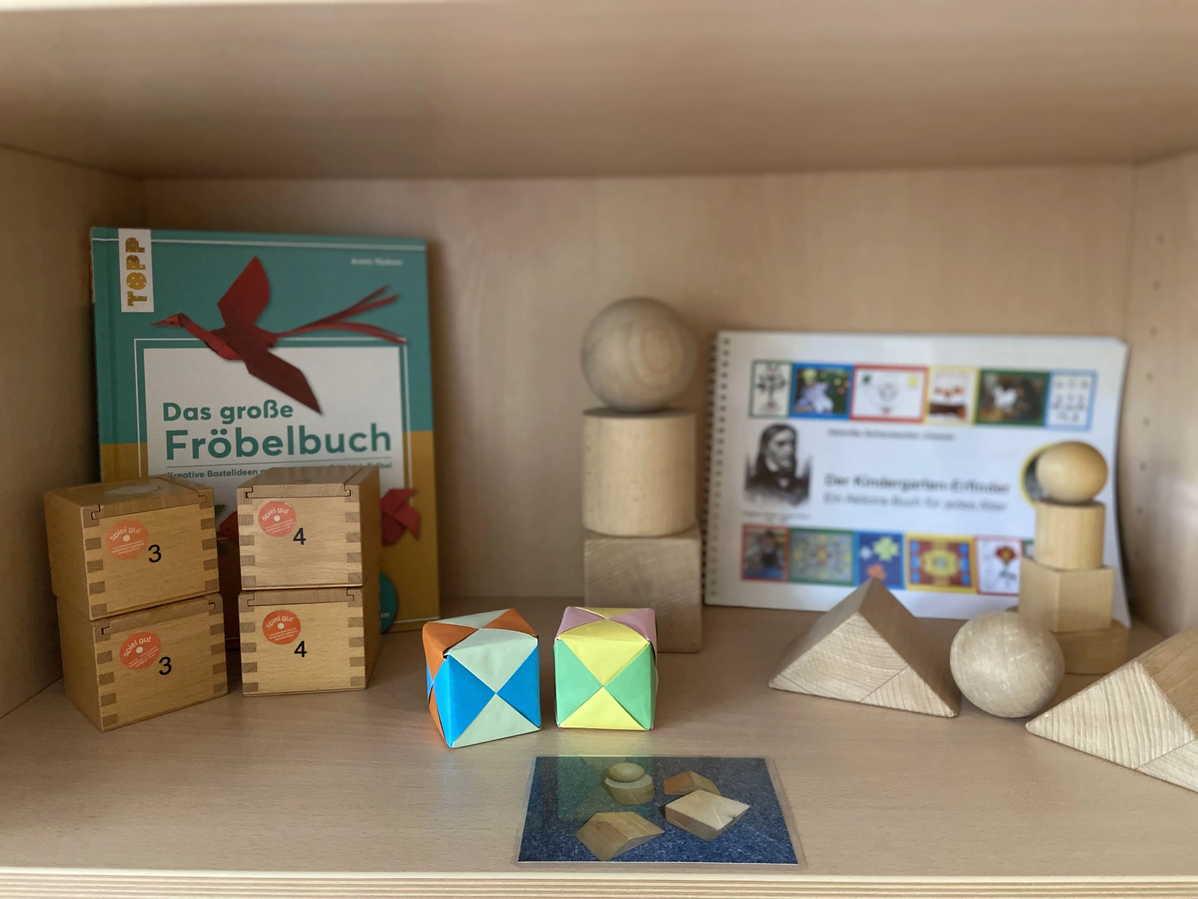 Regal mit Fröbel-Bauklötzen, Holzformen und pädagogischen Büchern über Friedrich Fröbel.