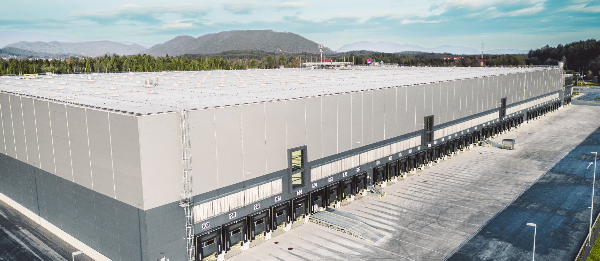 Large industrial warehouse with white metal roof, loading docks.