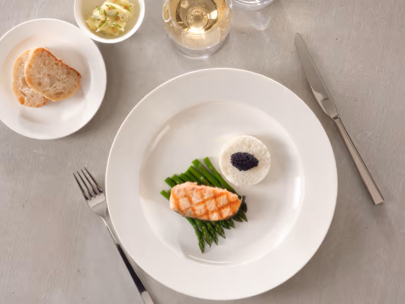Modern angerichtetes Fischgericht mit Lachs, Spargel und Reis auf einem weissen Porzellanteller.