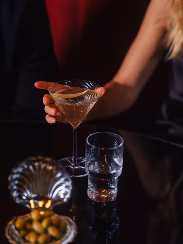 Elegantes Cocktailglas und Trinkglas auf einer stilvollen Barfläche in stimmungsvoller Atmosphäre.
