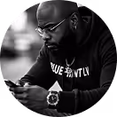 Man wearing glasses and hoodie looking at his phone in a close-up black and white photo.