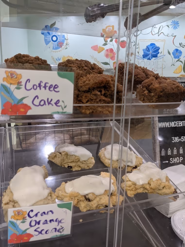 Display case with coffee cake on the top shelf and cranberry orange scones with white icing on the bottom shelf.