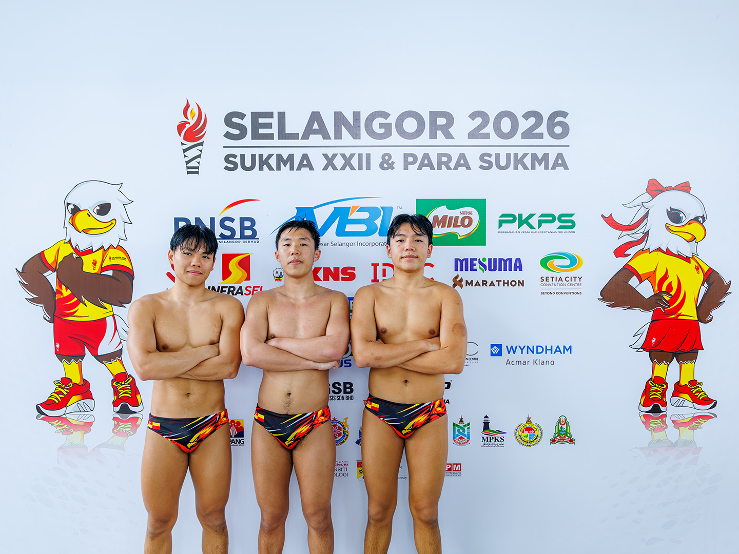 Aidan, Brandon, and Ethan Wong (left to right) standing together at the SUKMA XXII Selangor 2026 backdrop