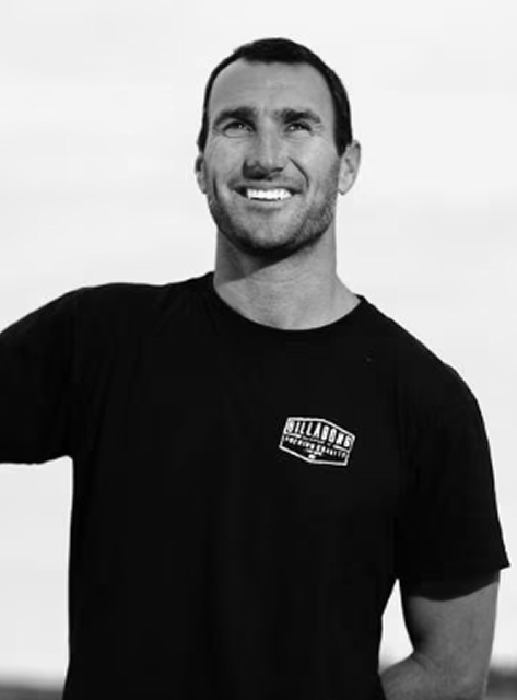Smiling man with short hair wearing a black Billabong t-shirt against a light background.